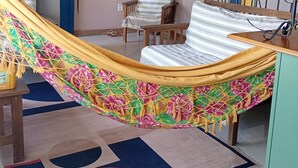 A hammock in a room with a bed, a chair, a lamp, and a staircase.