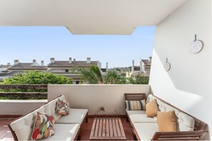 Eine Dachterrasse mit Sofagarnitur, einem kleinen Tisch und Blick auf Wohnhäuser.
