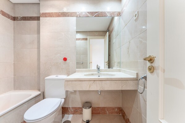 A bathroom with a toilet, sink, and mirror.