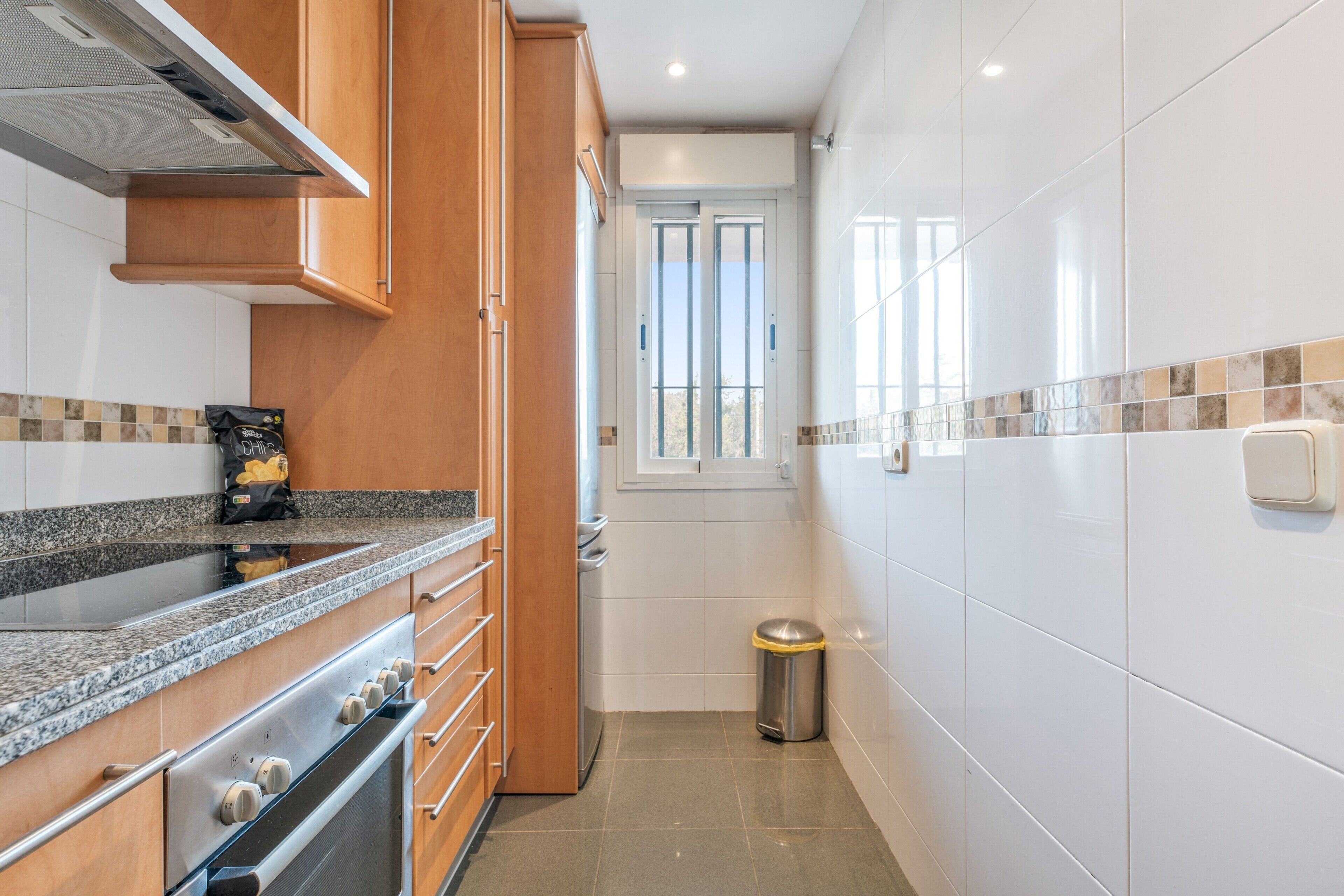 A compact kitchen with wooden cabinets, a stainless steel stove, and a tiled backsplash.