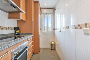 A compact kitchen with wooden cabinets, a stainless steel stove, and a tiled backsplash.