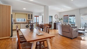 A spacious living area with a wooden dining table, a sofa, and a kitchen in the background. - Villa Horizonte with Sea Views, Wi-Fi and Air Conditioning (Tijoco Bajo)