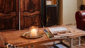 Uma mesa de madeira com uma vela, uma revista e uma almofada estampada com onça.