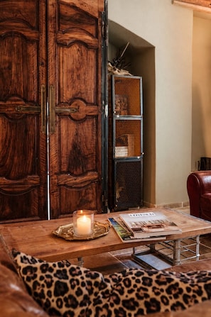 A wooden table with a candle, a magazine, and a leopard print cushion. - Bastide de 1855 au pied du Garlaban | Terrace, pool & Provencal charm (Aubagne)