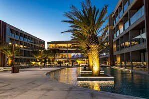 A modern building with a pool, palm trees, and a well-lit walkway. - Porto 2 Life Resort (Ipojuca)