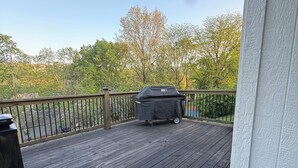 Una terraza de madera con una parrilla y una barandilla.