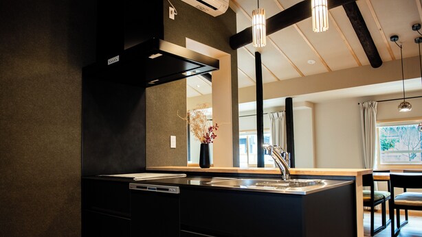 Una cucina moderna con isola centrale, elettrodomestici integrati e illuminazione a sospensione.