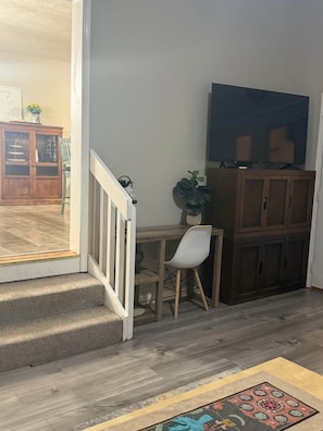 Een kamer met een houten bureau, een stoel, een televisie en een kast.