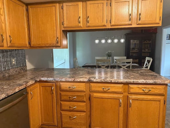 Una cocina con armarios de madera, encimera de granito y un comedor con mesa y sillas.