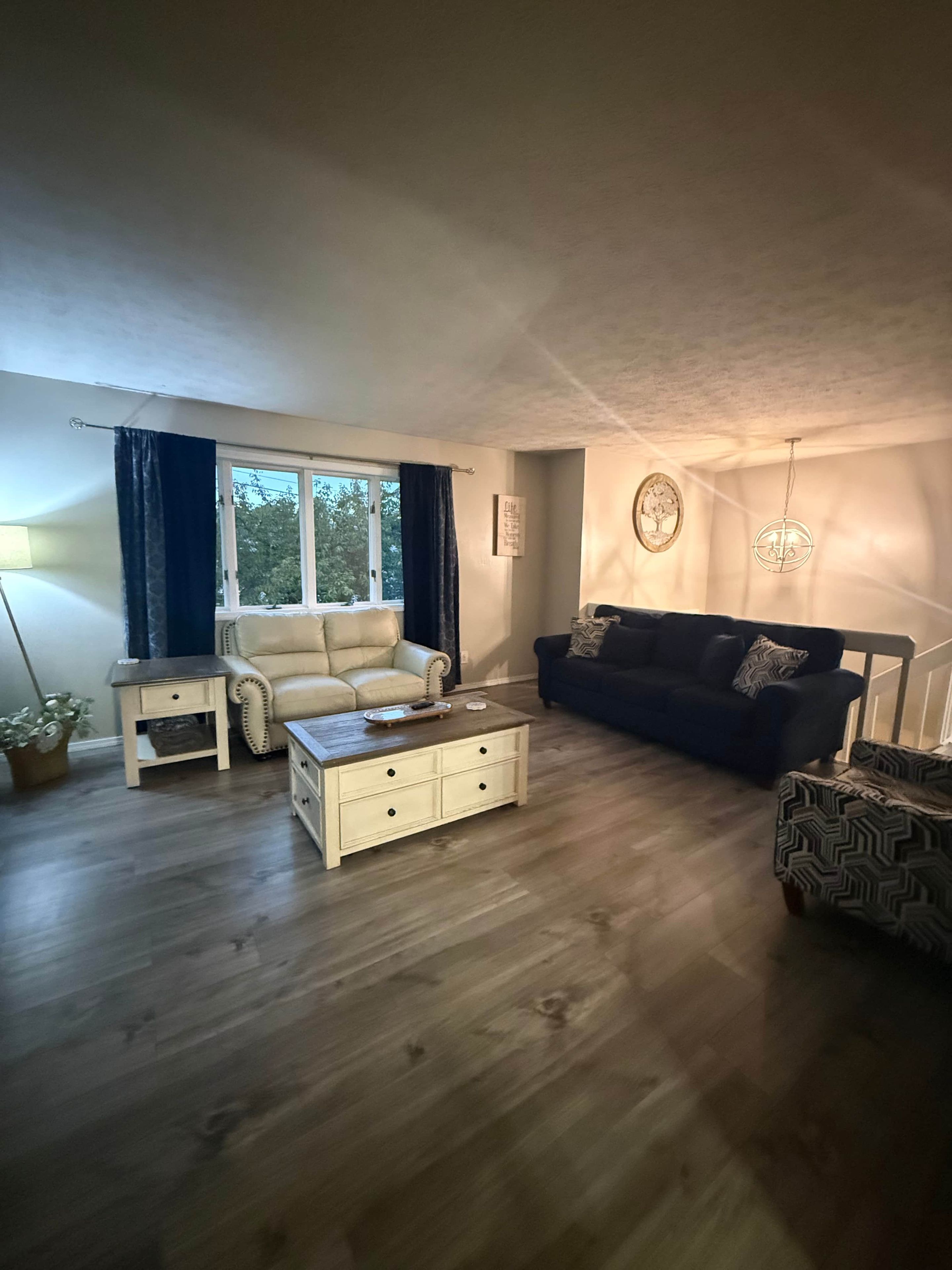Uma sala de estar com sofá, mesa de centro e janela com cortinas.