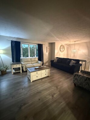 A living room with a sofa, a coffee table, and a window with curtains. - Sleeps 16+ • 5BR • Game Rooms • Near IU/Indy/Lake (Perry Township)