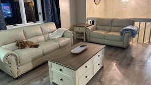 Un salon avec deux canapés, une table basse et un chien.