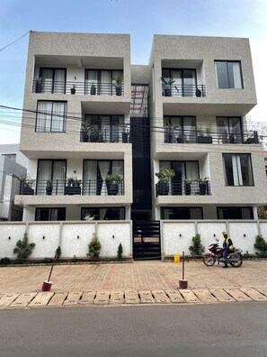 A modern multi-story residential building with balconies, potted plants, and a gated entrance. - Fabulous 2-bedroom apartment in vibrant Kigali for your stay (Kigali)