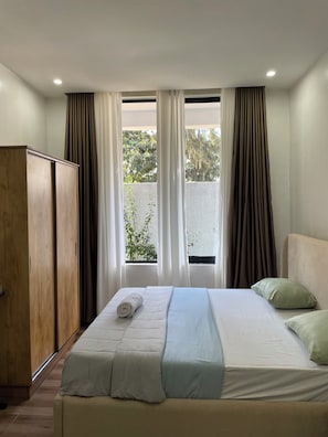 A bedroom with a bed, a wardrobe, and a window with curtains. - Fabulous 2-bedroom apartment in vibrant Kigali for your stay (Kigali)