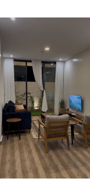 A modern living room with a sofa, chairs, a TV, and a large window with curtains. - Fabulous 2-bedroom apartment in vibrant Kigali for your stay (Kigali)