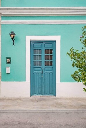 A teal building with a blue door, a wall-mounted light, and a small sign. - Rumi a perfect home near the PASEO GASTRONOMICO (Mérida)