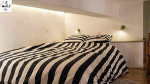 Un dormitorio con edredón a rayas, cabecera de madera y una pequeña alfombra.