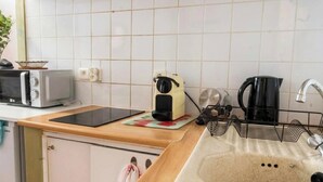 Una cocina con microondas, tostadora, hervidor y un lavabo con un jabonera con forma de oso.