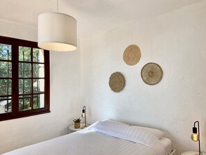 Una camera da letto con un letto, una finestra, una lampada a sospensione e tre decorazioni circolari appese al muro.