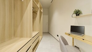 Ein modernes Zimmer mit einem Holzschrank, einem Schreibtisch mit einem Laptop und einem Stuhl.