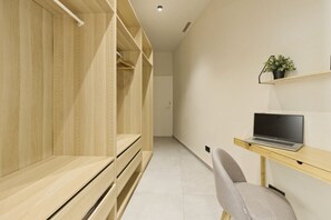 Ein modernes Zimmer mit einem Holzschrank, einem Schreibtisch mit einem Laptop und einem Stuhl.