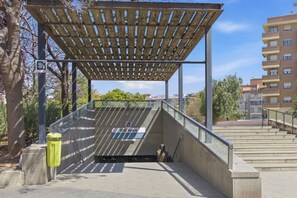 A covered outdoor area with a metal railing, a bench, and a trash bin. - Travel Habitat Jardines de Ayora 1 WIFI+AACC (Valencia)