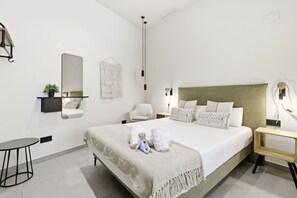 A modern bedroom with a large bed, bedside tables, a small round table, and a wall-mounted mirror. - Travel Habitat Jardines de Ayora 1 WIFI+AACC (Valencia)