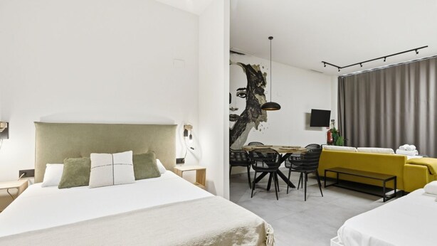 Ein modernes Hotelzimmer mit einem großen Bett, einem Essbereich mit Tisch und Stühlen sowie einer Couch.