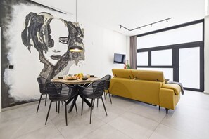 Ein zeitgemäßer Wohnraum mit Essbereich, einer Couch und einem großen Fenster.