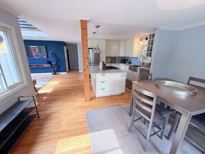Een moderne keuken met witte kasten, een eettafel en een groot keukenblok.