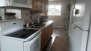 Una cocina con estufa, microondas, pileta y refrigerador.