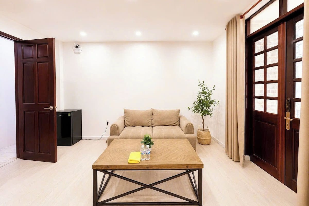 A room with a sofa, a coffee table, a potted plant, and a door.