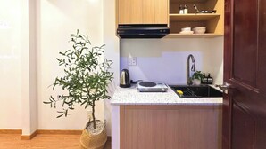 Una cocina moderna con armarios de madera, estufa integrada, un lavabo y un estante pequeño con utensilios de cocina.