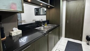 Una cocina moderna con encimera negra, pileta de acero inoxidable y muebles de madera.