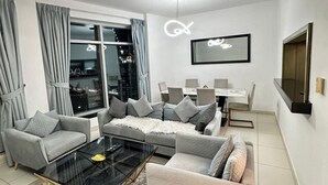 Una sala de estar moderna con un sofá, sillones, una mesa de centro de vidrio y un comedor con una mesa y sillas.