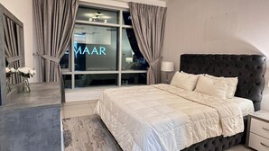 Un dormitorio con una cama grande, una mesita de noche, una ventana con cortinas y vistas a la ciudad.