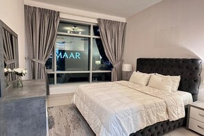 A bedroom with a large bed, a nightstand, a window with curtains, and a view of the city. - Elegant 2BR in Downtown Dubai  Skyline Views  Pool Gym (Dubai)