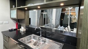 Una cocina moderna con encimera negra, pileta de acero inoxidable y un espejo grande que refleja el ambiente.