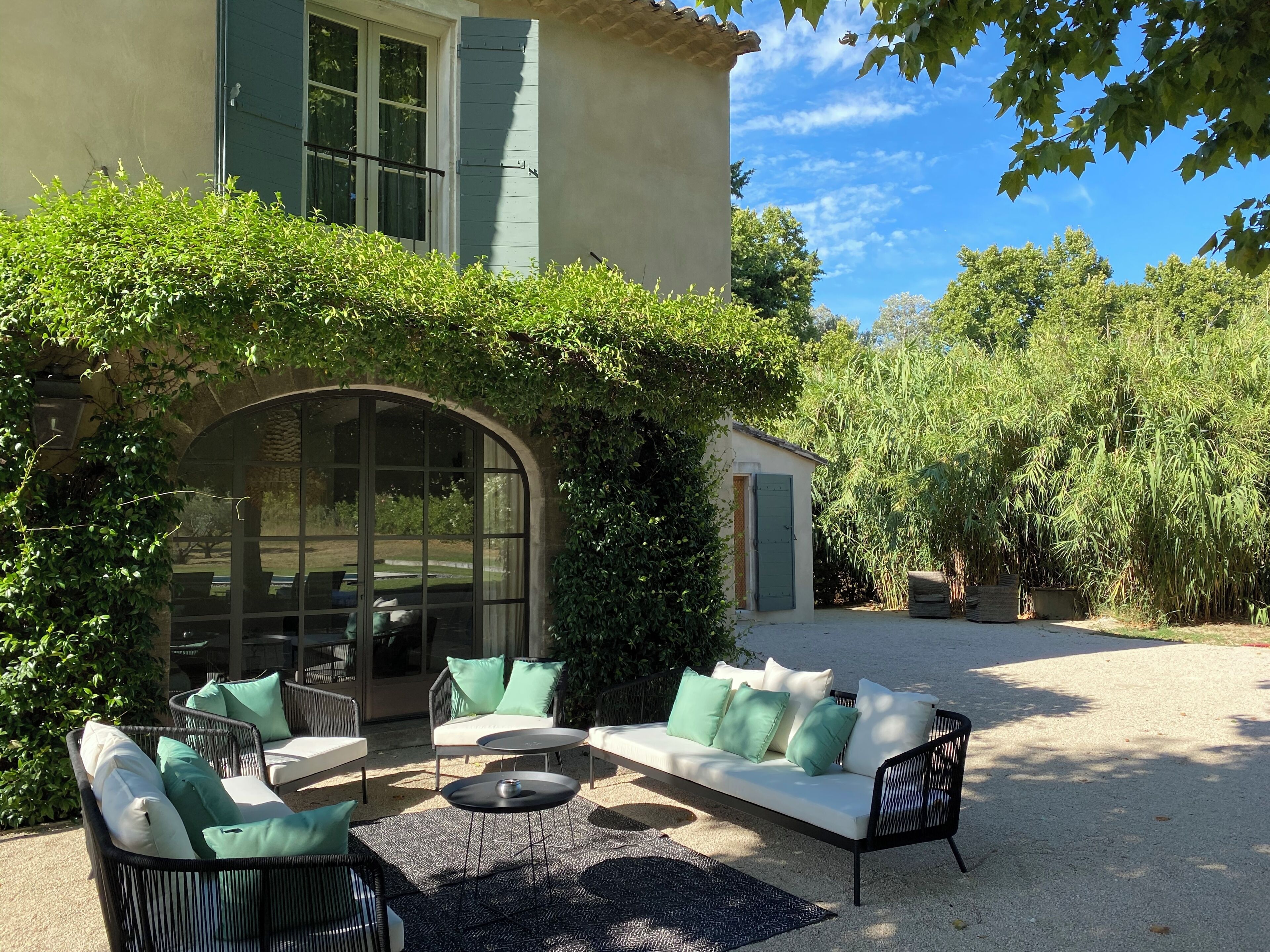 A patio with outdoor furniture, a glass door, and a building with a green door.