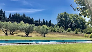 A pool with a clear blue sky, trees, and a grassy area. - Mas en Provence with swimming pool - comfort and relaxation (Eyragues)