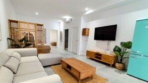 A modern living room with a sectional sofa, a wooden coffee table, a TV, and a teal refrigerator. - Travel Habitat Jesus-Patraix Family Apartment (Valencia)