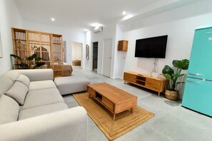 A modern living room with a sectional sofa, a wooden coffee table, a TV, and a teal refrigerator. - Travel Habitat Jesus-Patraix Family Apartment (Valencia)
