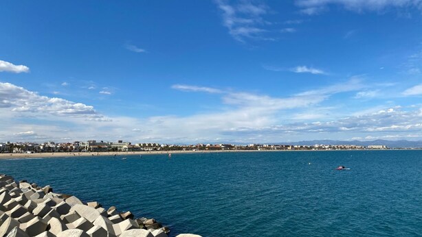 A coastal view with a clear sky, a rocky breakwater, and a distant shoreline with buildings. - Travel Habitat Jesus-Patraix Family Apartment (Valencia)