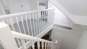 Una escalera con barandilla blanca, escalones alfombrados y una zona de descanso.