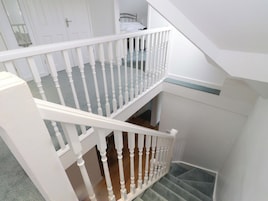 Una escalera con barandilla blanca, escalones alfombrados y una zona de descanso.