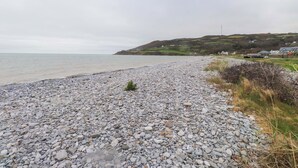 Una playa de guijarros con vista al mar y colinas al lejano.