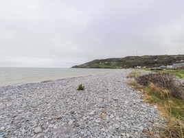 Una playa de guijarros con vista al mar y colinas al lejano.