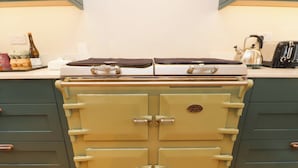 A vintage stove with two ovens, a kettle, and a toaster on a kitchen counter. - Belan Wen (Beaumaris)