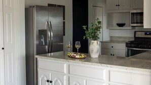 A kitchen with a stainless steel refrigerator, a microwave, and a stove. There is a fruit platter on the counter and a vase with a plant.