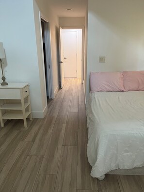 A bedroom with a bed, a nightstand, a door, and a hallway. - 4br Ranch Style Home - Central Austin (Austin)